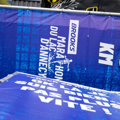 Totems personnalisés en pont scénique pour indiquer le kilométrage sur le parcours du Brooks Marathon du Lac d'Annecy
